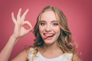 Komik genç kadın düz dört gözle ve gülümsüyor ise biteviye-in onun dili gösteren. Ayrıca kız ok sembolü ile parmaklarını gösteriyor. Pembe arka plan izole.