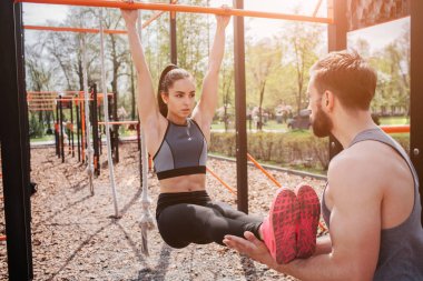 Kız ellerini yatay çubuk üzerinde tutarak ve için adam arıyor. Adam bacaklarını düz ve seyir ona tutuyor.