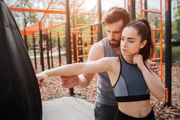 스포티 한 남자와 여자는 공원에서 서 하 고 함께 운동. 권투 소녀 하려고 그녀의 트레이너는 그녀의 움직임을 유도 하는 동안. — 스톡 사진