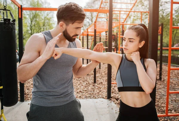 Un uomo bello e forte sta addestrando il suo studente. Lui le sta insegnando. Ragazza sta tenendo la mano dritta e tenendo le dita in un pugno . — Foto Stock