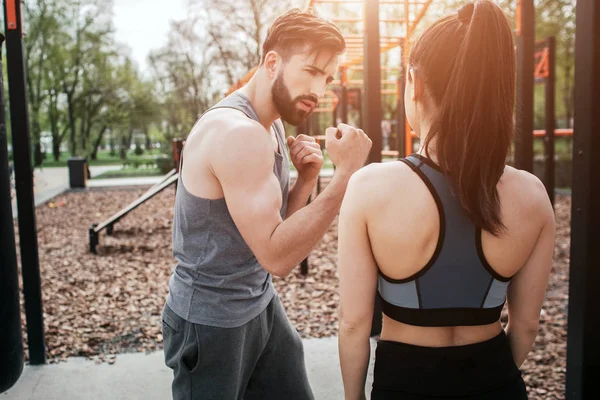 젊은 남자와 ouside 공원에서 운동 하는 여자의 사진. 그가 올바른 방법으로 권투를 수행 하는 방법을 보이고 있다. 그녀가 그것을 보고는. — 스톡 사진