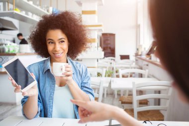 Afro Amerikalı kız arkadaşıyla büyük bir telefon gösterilen ve çay içme mavi gömlekli bir resim. Gülümsüyor.