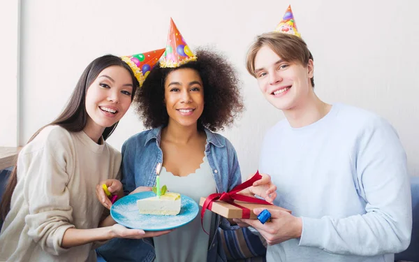 Bela foto de uma aniversariante e seus amigos. Menina asiática tem um pedaço de bolo. O tipo tem um presente nas mãos. Todos eles são felizes . — Fotografia de Stock