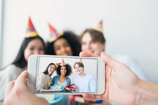 Jemand macht ein Foto am Telefon. Es gibt ein Mädchen, das Geburtstag hat, und ihre Freunde, die versammelt sind. Sie posieren und lächeln vor der Kamera. — Stockfoto