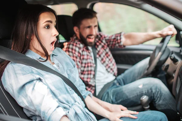 Les jeunes conduisent très vite. Ils font un arrêt inattendu. Guy crie pendant que la fille garde la bouche ouverte et regarde droit sur la route . — Photo