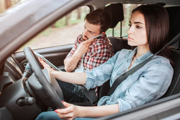 Une photo de couple voyageant en voiture. Guy parle au téléphone pendant que la fille conduit et fait attention à la route. Elle a l'air sérieuse . — Photo