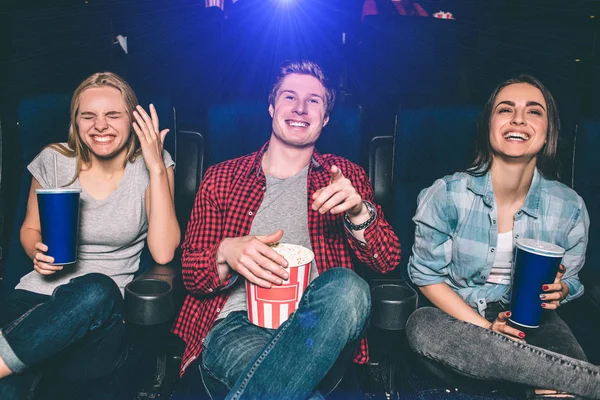 Schönes Bild von glücklichen Menschen, die im Kinosaal lachen. Sie schauen auf den Bildschirm und lächeln. Mädchen und Jungen sehen absolut umwerfend und glücklich aus. — Stockfoto