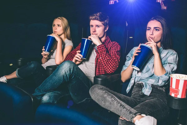 Трое друзей сидят вместе и пьют кокаин одновременно. Они смотрят кино. Молодые люди серьезны и сосредоточены на наблюдении . — стоковое фото
