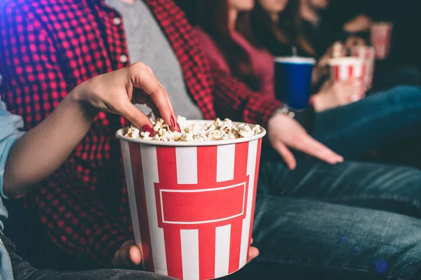 Close up of beautiful red basket with popcorn. Guy is holding it. Girls hand is taking some popcorn from it. — Stock Photo, Image
