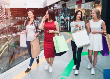 Alışveriş merkezinde kadın şirketidir. Onlar üzerinde iki gruba ayrılır. Asyalı kız sarışın arkadaşı telefon gösterilirken Kırmızı elbiseli kız telefonda konuşuyor. Güzel ve neşeli görünüyorlar.