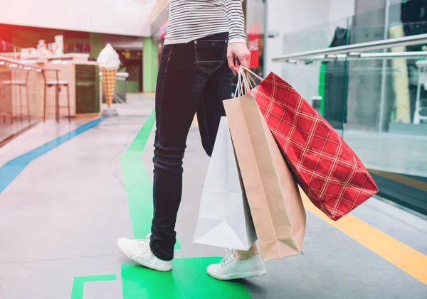 Una imagen de la gente parte baja del cuerpo. El humano sostiene las bolsas de comprassin la mano izquierda. Este humano está en el centro comercial. . — Foto de Stock