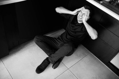 Siyah elbiseli genç bir adamın siyah beyaz fotoğrafı mutfakta tek başına oturmuş ve çığlık atıyordu. Ellerini başının üstüne koy ve sakin olmaya çalış. Rahatsızlık ve acı. Çaresizlik.