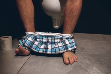 Kıllı bacaklı, kısa pantolonlu adamları kes. Adam tuvalette ya da tuvalette esrara oturuyor. Dışkılama yapıyorum. Tuvalette yalnızdım. Kağıt sol tarafta yuvarlanıyor..