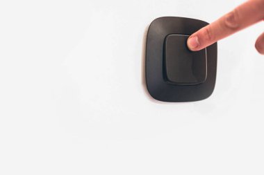 Kapat ya da parmağınla duvardaki ışık düğmesini kapat. Kafkas eli. Kontrastlı resim. Beyaz duvar ve siyah ışık düğmesi. Yan görünüm.