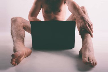 Genç çıplak adam porno izliyor ve mastürbasyon yapıyor.
