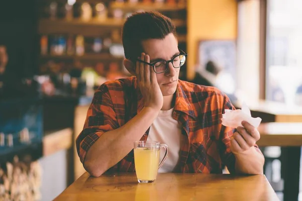Sick student blowing his nose into a tissue. — Stock Photo, Image