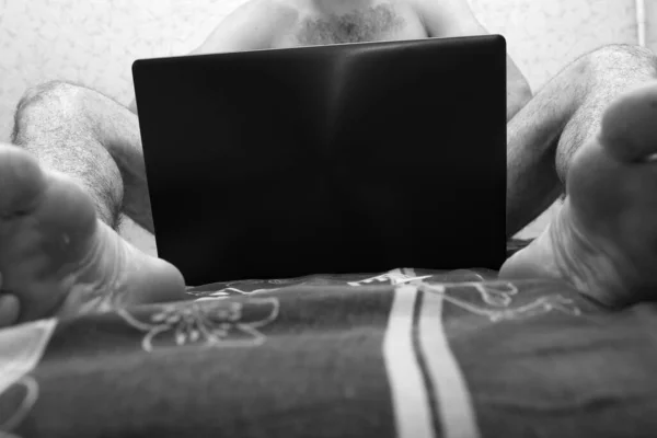 Jovem homem nu com corpo peludo sentar e segurar laptop entre as pernas. Cobre-te. Vista baixa. Foto em preto e branco. Intimidade. Vista para corte . — Fotografia de Stock