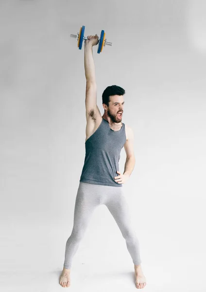 Hombre flaco entrenando su músculo bíceps. Un tipo levantando una mancuerna. formación de jóvenes estudiantes para fortalecerse — Foto de Stock
