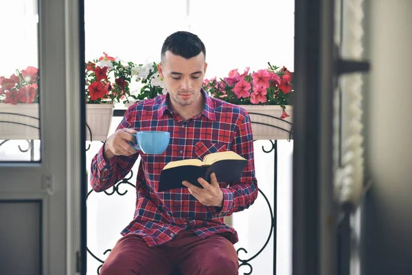 Barbuto concentrato che legge libri e beve caffè o tè — Foto Stock
