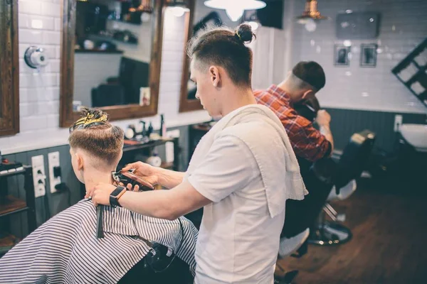 Cabeleireiro faz penteado um homem com um clipe na cabeça em um salão de cabeleireiro . — Fotografia de Stock