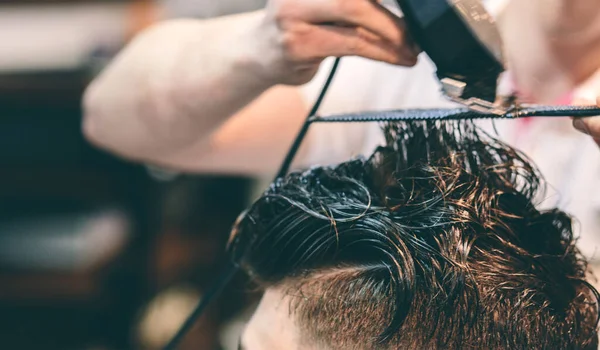 Cabeleireiro faz penteado um homem com um clipe na cabeça em um salão de cabeleireiro — Fotografia de Stock