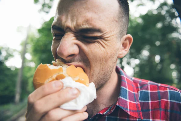 El hombre está comiendo en el parque y disfrutando de deliciosa comida — Foto de Stock