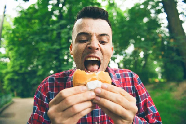 Homem está comendo no parque e desfrutando de deliciosa comida — Fotografia de Stock