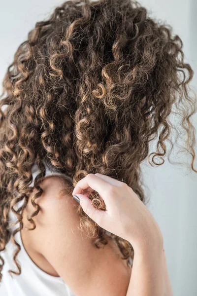 Вертикальная фотография молодой женщины с великолепными вьющимися каштановыми волосами. Прическа с объемом. Поза на белом фоне . — стоковое фото
