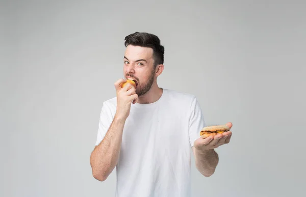 El chico come una manzana y una hamburguesa. El hombre hace la elección entre comida rápida y saludable. Sabroso y útil. El dilema de elegir un estilo de vida diferente — Foto de Stock