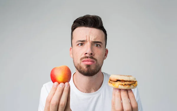 El hombre hace la elección entre comida rápida y saludable. Sabroso y útil El dilema de elegir un estilo de vida diferente — Foto de Stock