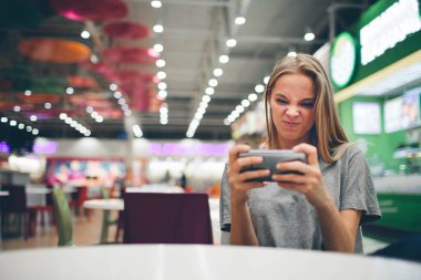 Restoran terasında, odaklanmamış bir geçmişi olan akıllı bir telefonla mesajlaşan kız..