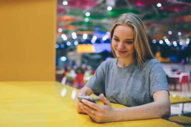 Restoran terasında, odaklanmamış bir geçmişi olan akıllı bir telefonla mesajlaşan kız..