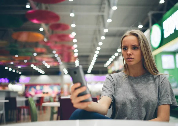 Egy lány sms-ezik az okostelefonon egy étterem teraszán, koncentrálatlan háttérrel — Stock Fotó