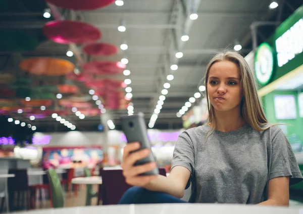 Dziewczyna smsy na smartfonie w restauracji taras z nieostrym tle — Zdjęcie stockowe