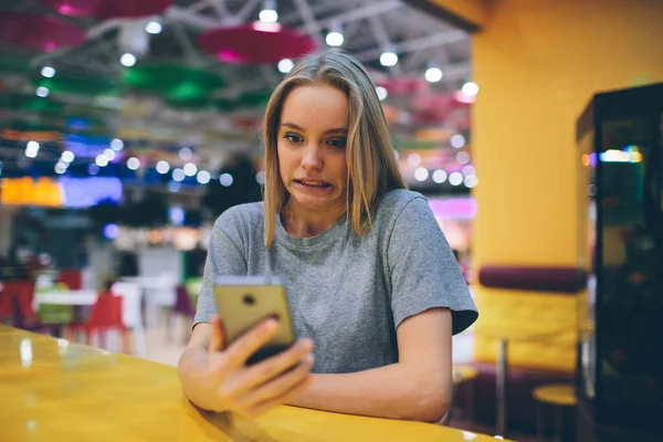 在一个没有聚焦背景的餐厅平台上用智能手机发短信的女孩 — 图库照片