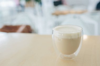 Cappuccino latte ya da modern bardakta çift dipli sütlü kahve. Masanın üzerinde. Yakın çekim görüntüsü. Arka planda bulanık bir kafe. Metin için yer var..
