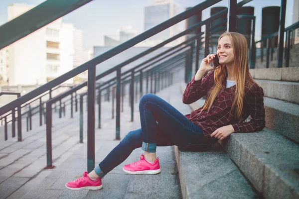 Das Mädchen sitzt auf den Stufen und telefoniert — Stockfoto