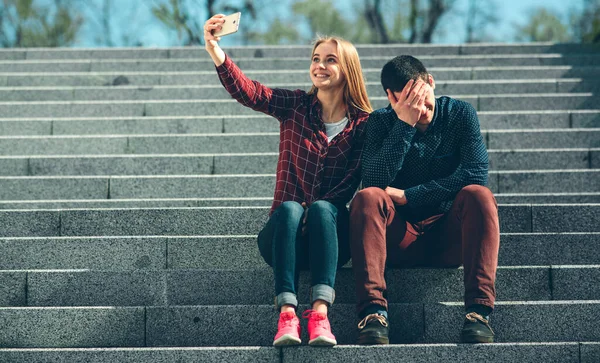 Woman makes selfie, but her boyfriend does not want to. Dependence on photo and social networking. Narcissism and simulation of happy life. — Stock Photo, Image