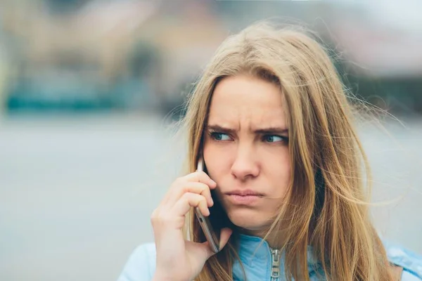 Loira linda emocional falando ao telefone ao ar livre. Feminino Rostos corruptos e se entrega a conversar com amigos no celular . — Fotografia de Stock