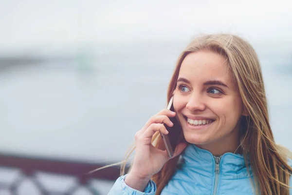 Loira linda emocional falando ao telefone ao ar livre. Feminino Rostos corruptos e se entrega a conversar com amigos no celular . — Fotografia de Stock