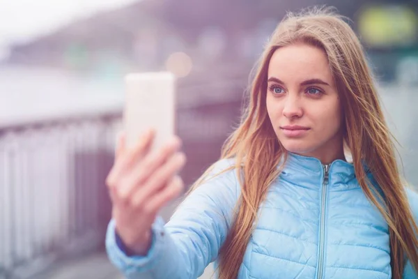 Csinos nő, aki szelfit csinál. Gyönyörű lány sétál az utcán, és fényképez néhány látnivalót. Szőke lefényképezte magát, Instagram — Stock Fotó