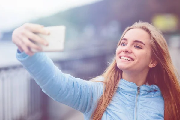 Csinos nő, aki szelfit csinál. Gyönyörű lány sétál az utcán, és fényképez néhány látnivalót. Szőke lefényképezte magát, Instagram — Stock Fotó