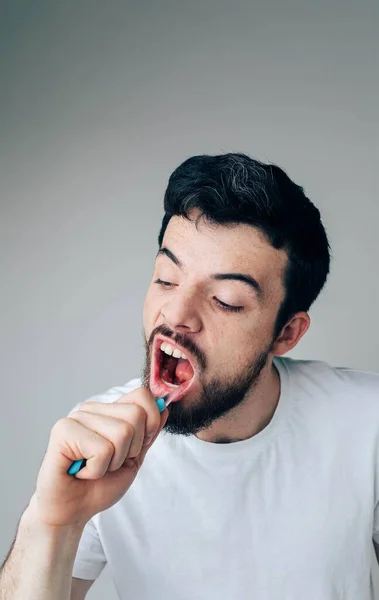 Genç adam arka planda izole edilmiş. Diş fırçasıyla diş temizleyen çalışkan ciddi bir adam. Ağız ve diş sağlığına dikkat et. Dikey resim ve resmi kapat — Stok fotoğraf