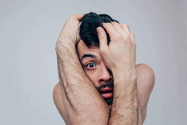 Young man isolated over background. Unbalanced mentally an disordered guy look on camera and hide face with hands. Mad and confused male person. — Stock Photo, Image