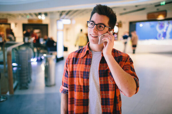 человек держать смартфон на фоне торгового центра
