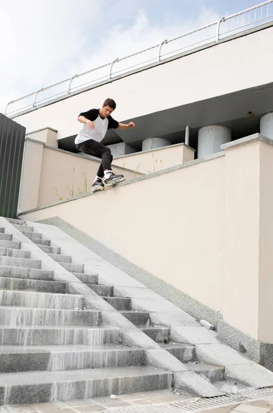 Bonito patinador profissional jovem patinador na rua fora. Edifícios urbanos com vista branca. Luz do dia . — Fotografia de Stock