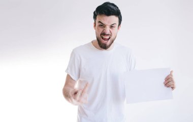 Beyaz bir kağıt parçası tutan sakallı bir adam. Kızgın genç adam kameraya parmaklarını gösteriyor..