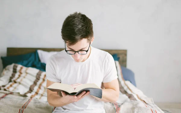 Uomo che legge un libro sul suo letto a casa — Foto Stock