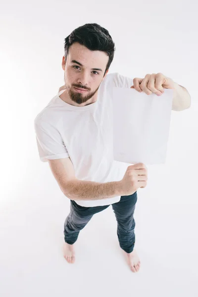 Hombre barbudo sosteniendo una hoja de papel blanco en blanco — Foto de Stock