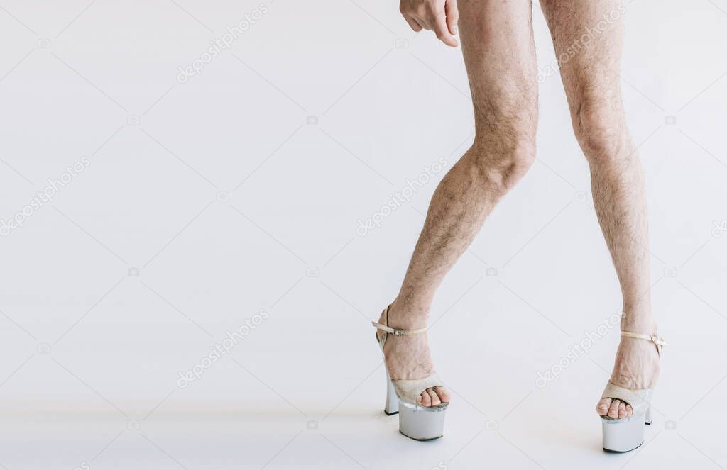 Cut view of long curved legs in white womans shoe on high heels. Transvestite like to wear female footwear. Side view. Isolated over background.